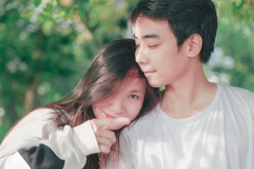 Teen couple standing close outdoors among green trees, illustrating Vermont's two-sided age window