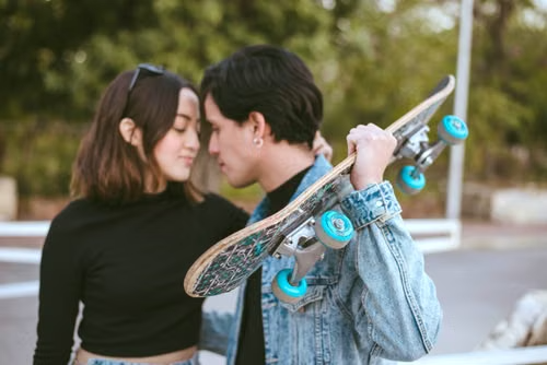 Young couple standing face to face outdoors with a skateboard, illustrating Connecticut's three-year age-gap element