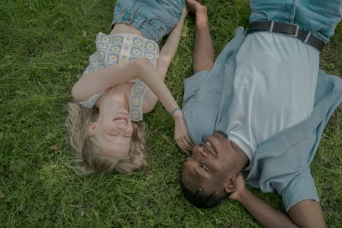 Teen couple lying on grass holding hands, illustrating Rhode Island's actor-age floor