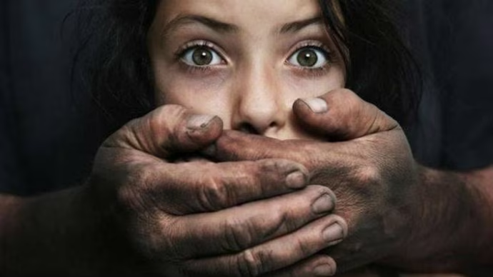 Close-up of a frightened young person with a hand covering her mouth