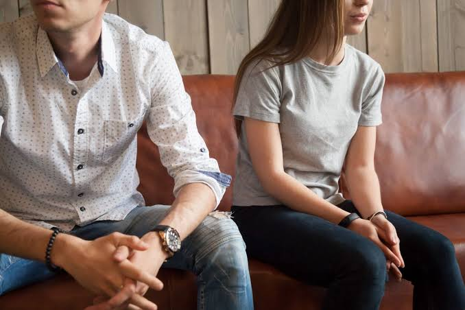 Young man and young woman sitting apart on a couch after an argument