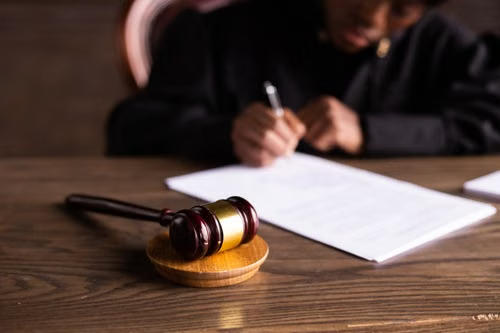 Judge's wooden gavel on a desk while a judge signs court paperwork, illustrating Michigan statutory offense penalties